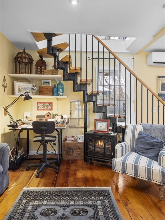 interior space featuring wood-type flooring, a wood stove, and a wall mounted AC