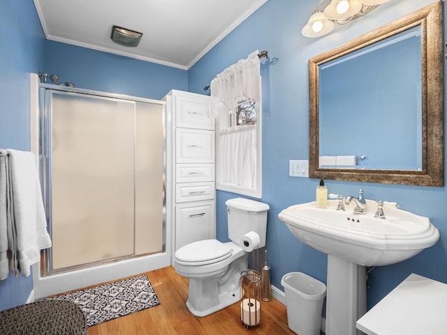 bathroom with hardwood / wood-style flooring, toilet, ornamental molding, and walk in shower