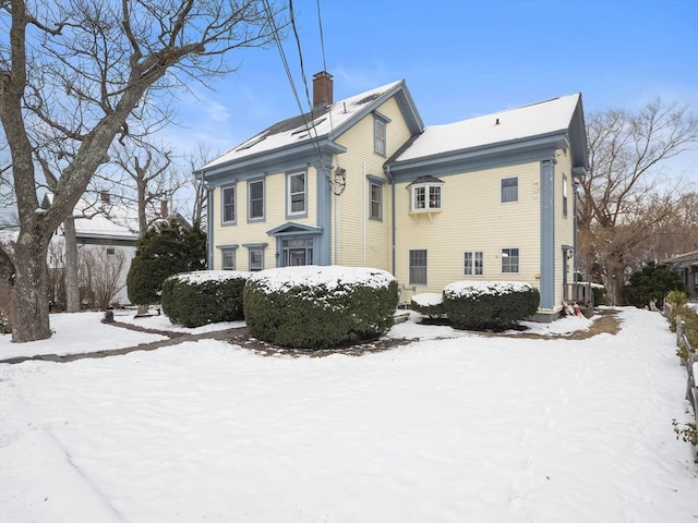 snow covered back of property featuring central AC unit