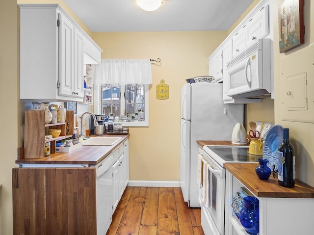 kitchen featuring white appliances, wooden counters, sink, and white cabinets