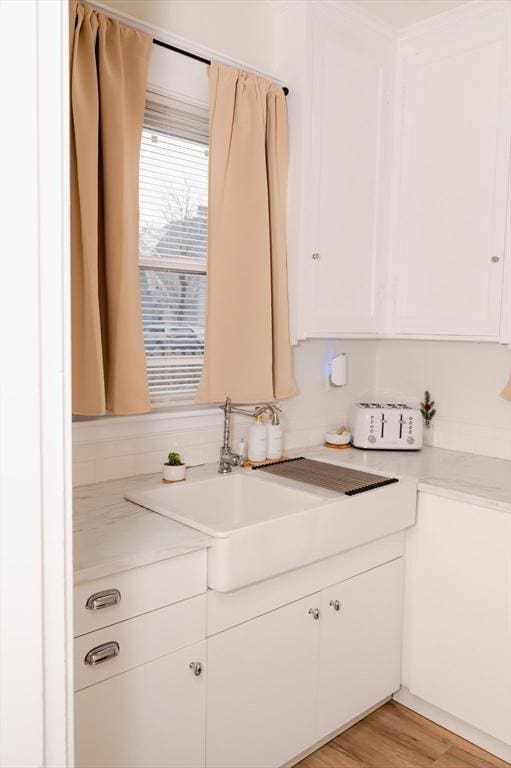 kitchen featuring sink, white cabinetry, and light wood-type flooring