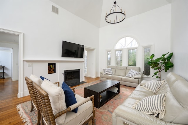 living room with a chandelier, hardwood / wood-style floors, and a high ceiling