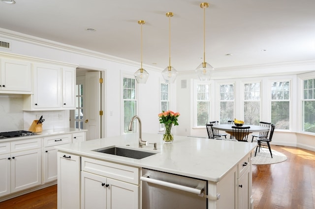 kitchen with hardwood / wood-style flooring, ornamental molding, sink, pendant lighting, and appliances with stainless steel finishes