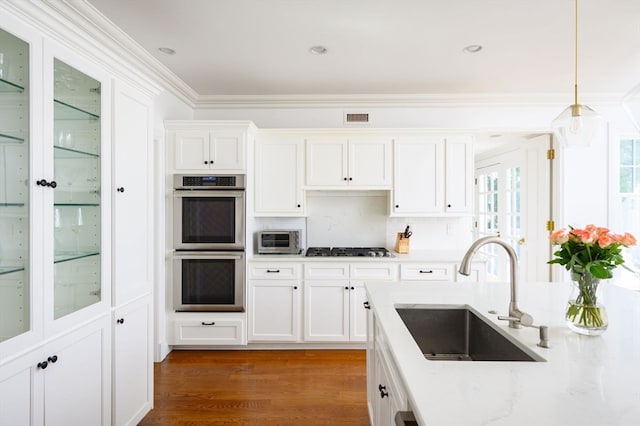 kitchen with sink, appliances with stainless steel finishes, crown molding, and white cabinetry