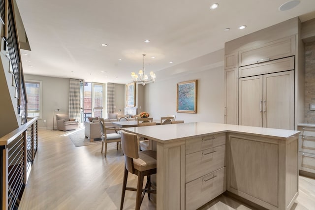 kitchen with a kitchen island, light hardwood / wood-style floors, a chandelier, light brown cabinetry, and decorative light fixtures