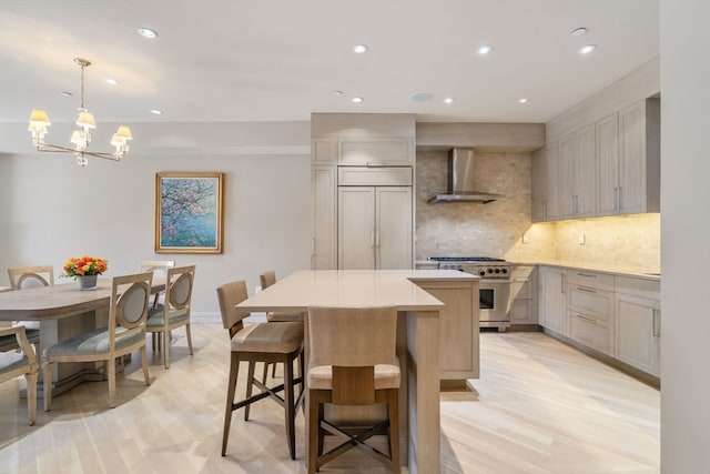 kitchen featuring pendant lighting, light hardwood / wood-style flooring, wall chimney range hood, a center island, and high quality appliances