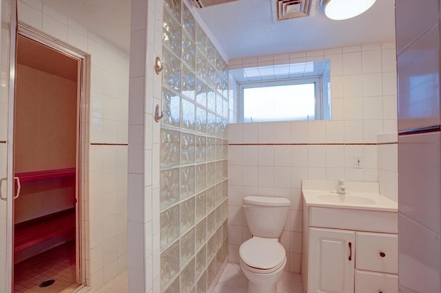 bathroom featuring vanity, toilet, an enclosed shower, and tile walls