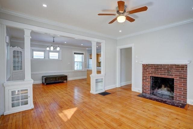 unfurnished living room with ceiling fan with notable chandelier, a fireplace, light wood-type flooring, and crown molding