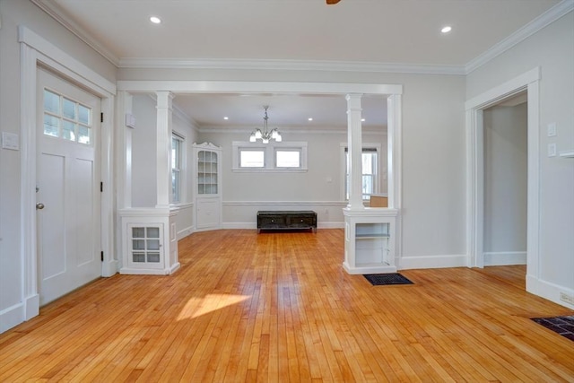 unfurnished living room with ornate columns, crown molding, light hardwood / wood-style floors, and an inviting chandelier