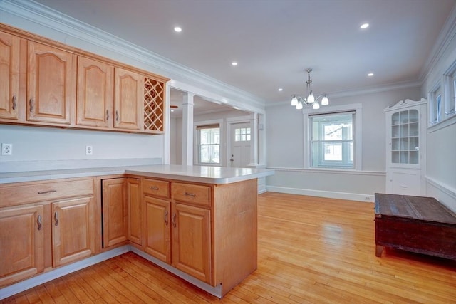 kitchen featuring light wood-type flooring, kitchen peninsula, hanging light fixtures, and ornamental molding