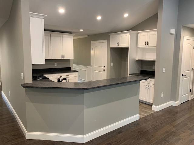 kitchen featuring dark wood-type flooring, sink, kitchen peninsula, white cabinetry, and vaulted ceiling