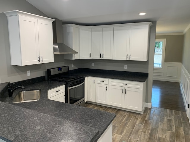 kitchen with stainless steel range with gas stovetop, wall chimney exhaust hood, and white cabinets