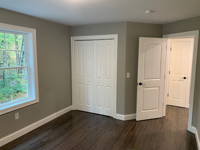 unfurnished bedroom with dark wood-type flooring and a closet