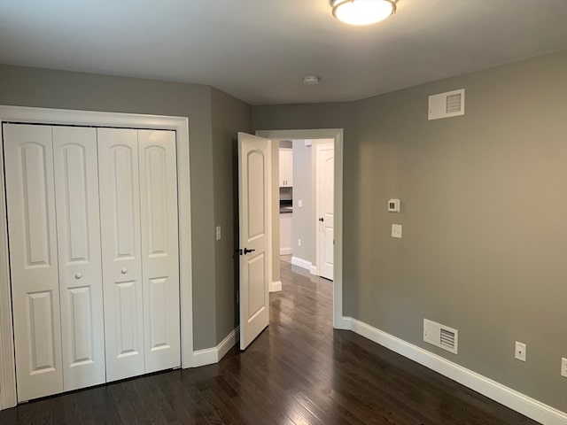 unfurnished bedroom with dark wood-type flooring and a closet