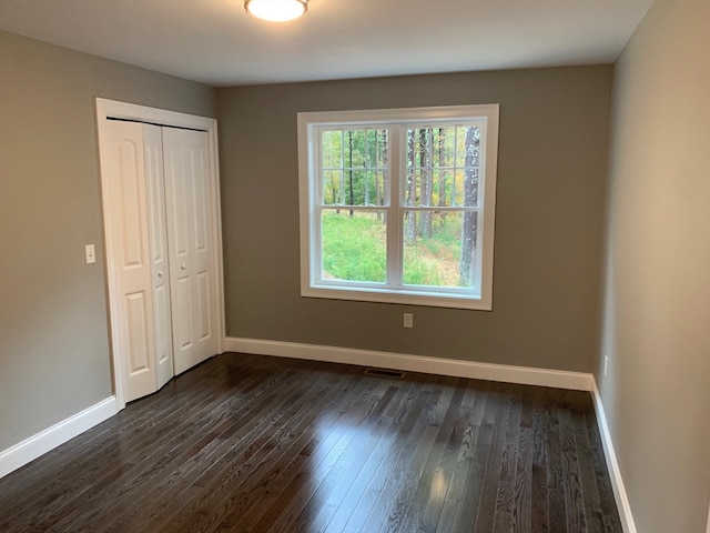 unfurnished bedroom featuring a closet and dark hardwood / wood-style floors