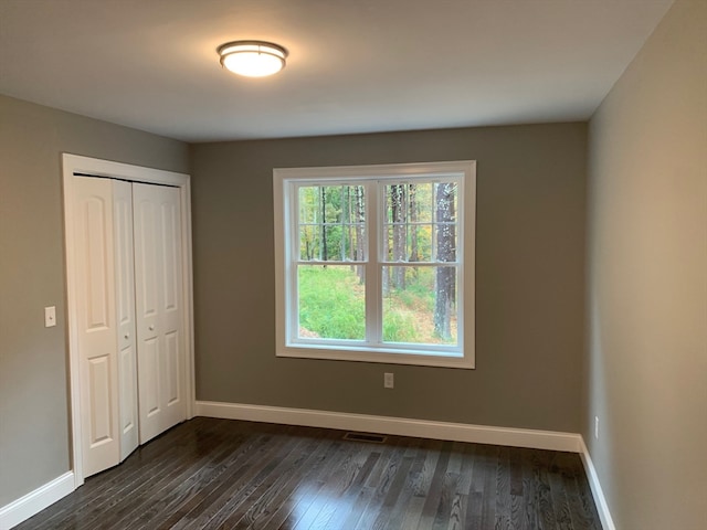 unfurnished bedroom featuring a closet and dark hardwood / wood-style flooring