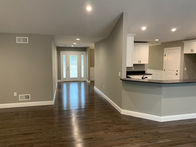 kitchen featuring kitchen peninsula, white cabinets, and dark hardwood / wood-style flooring