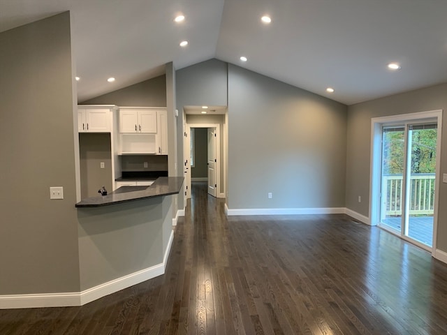 kitchen with kitchen peninsula, lofted ceiling, dark hardwood / wood-style flooring, and white cabinets