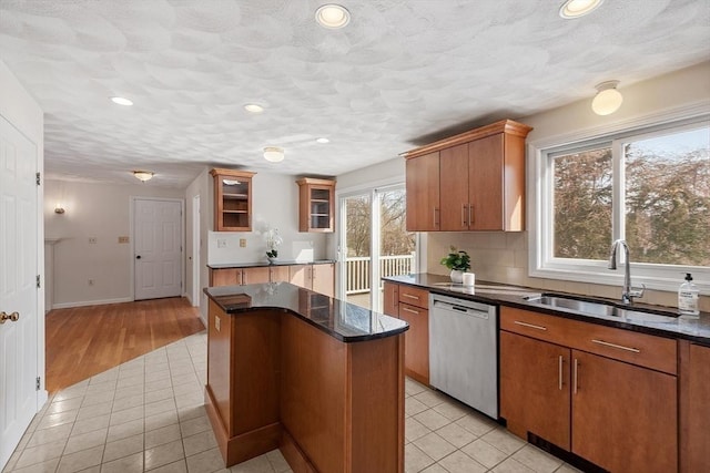 kitchen with a sink, light tile patterned floors, dishwasher, and a center island