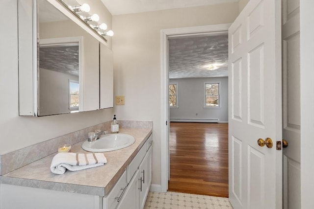 bathroom with baseboards, tile patterned floors, a textured ceiling, vanity, and a baseboard heating unit