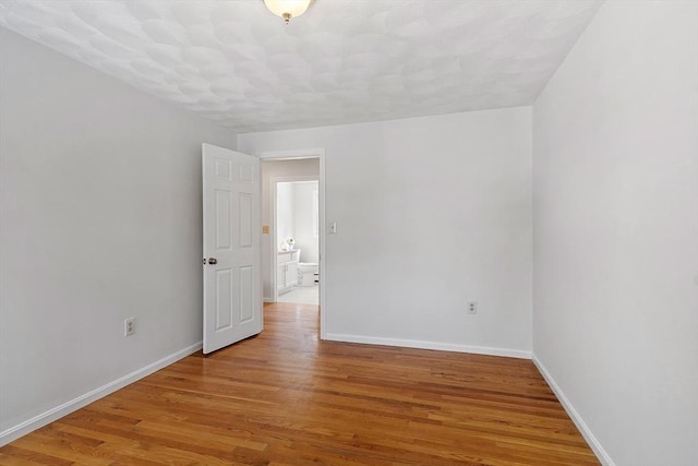 spare room with light wood-type flooring and baseboards