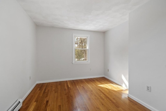 empty room with a baseboard radiator, baseboards, and wood finished floors