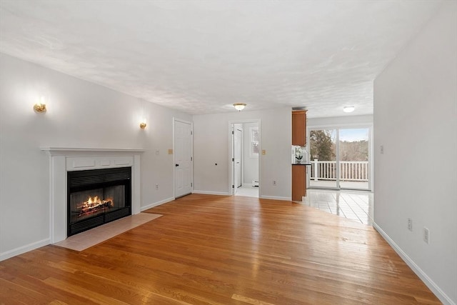 unfurnished living room featuring a fireplace with flush hearth, light wood-style flooring, and baseboards