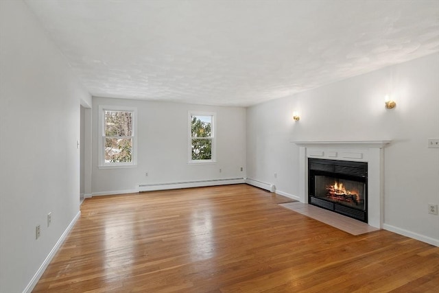 unfurnished living room featuring a fireplace with flush hearth, a baseboard heating unit, baseboards, and wood finished floors