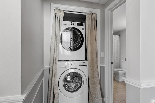 laundry area with laundry area, stacked washing maching and dryer, and light tile patterned flooring