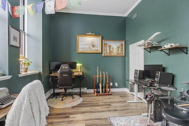 home office featuring light wood-style floors, baseboard heating, crown molding, and baseboards