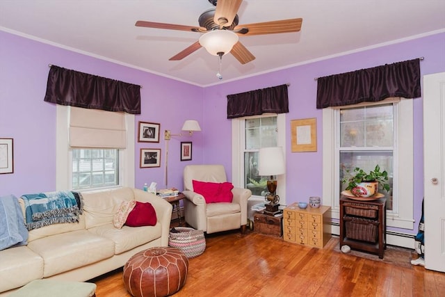 living room featuring baseboard heating, ceiling fan, ornamental molding, and hardwood / wood-style floors