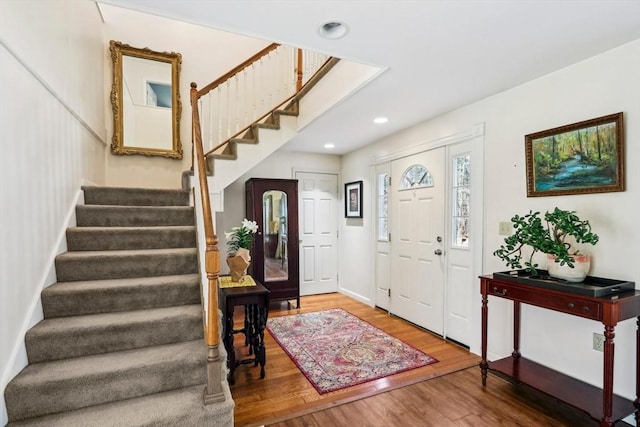 foyer entrance with recessed lighting, wood finished floors, and stairway