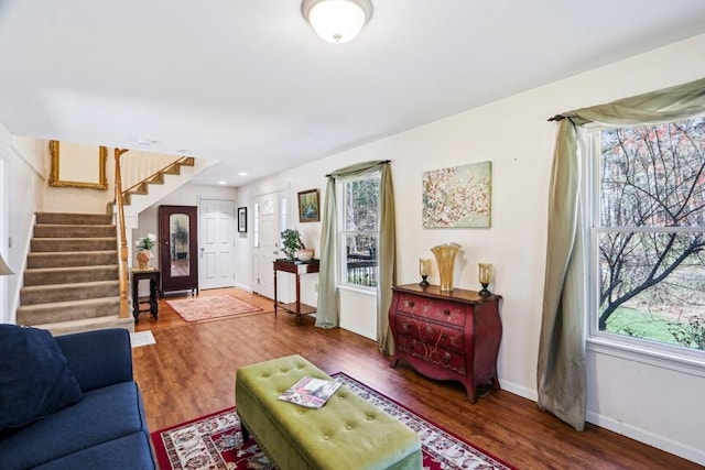 living room featuring a healthy amount of sunlight, baseboards, stairs, and wood finished floors