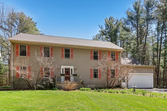 colonial-style house with an attached garage, a front yard, and aphalt driveway