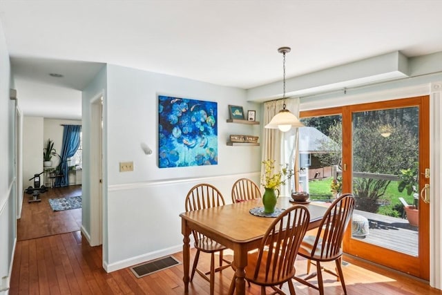 dining space with baseboards, hardwood / wood-style flooring, and visible vents