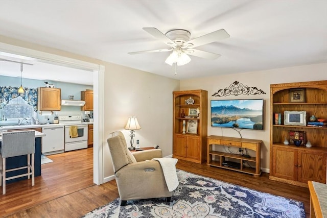 living area featuring baseboards, a ceiling fan, and wood finished floors