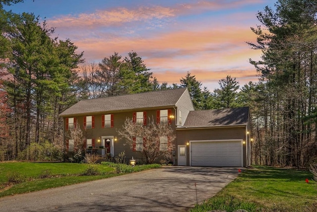 colonial inspired home with a lawn, a garage, and concrete driveway