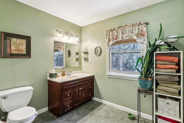 bathroom featuring toilet, baseboards, tile patterned flooring, and vanity