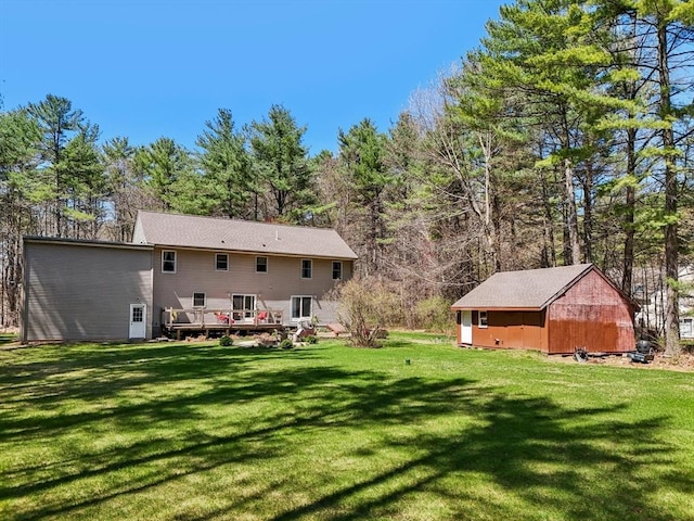 back of property featuring a lawn, an outbuilding, a wooden deck, and a shed