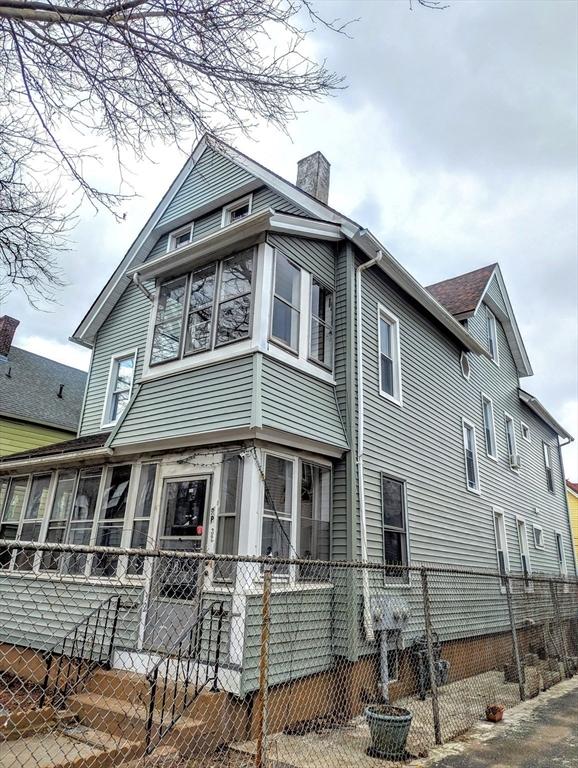 view of side of property featuring a fenced front yard, a chimney, and a sunroom