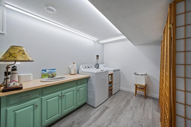 107 Washington St, Pembroke, MA 02359 - laundry area featuring cabinet space, light wood-style floors, washer and clothes dryer, and a textured ceiling