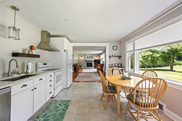 107 Washington St, Pembroke, MA 02359 - kitchen with white appliances, wall chimney range hood, a fireplace with raised hearth, and plenty of natural light