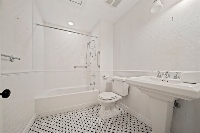 bathroom featuring tile walls, tiled shower / bath, toilet, and tile patterned flooring