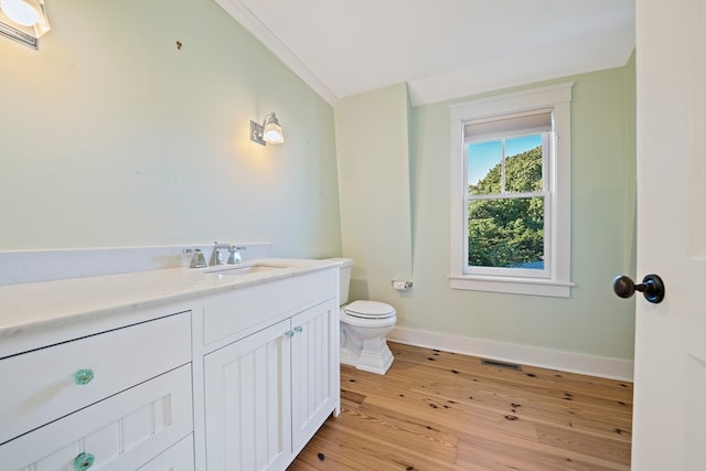 bathroom featuring toilet, hardwood / wood-style flooring, ornamental molding, and vanity