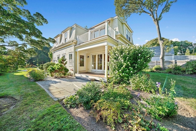 rear view of property featuring a balcony, a yard, and a patio