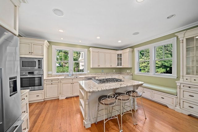 kitchen with a kitchen island, a healthy amount of sunlight, light wood-type flooring, and appliances with stainless steel finishes