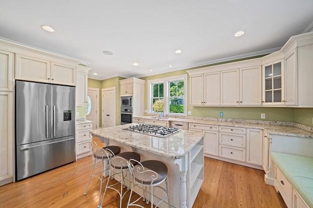 kitchen with a kitchen island, stainless steel appliances, light hardwood / wood-style floors, and ornamental molding