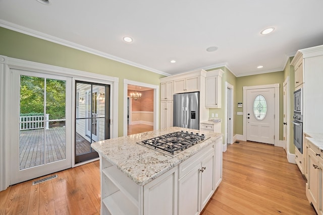 kitchen featuring ornamental molding, light stone countertops, appliances with stainless steel finishes, white cabinets, and light hardwood / wood-style floors