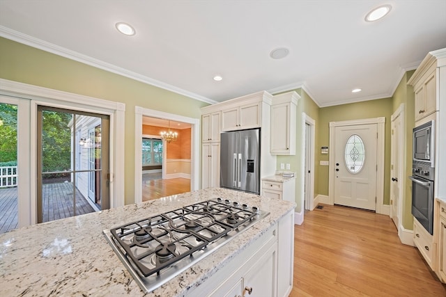 kitchen featuring an inviting chandelier, light stone countertops, appliances with stainless steel finishes, light hardwood / wood-style floors, and ornamental molding