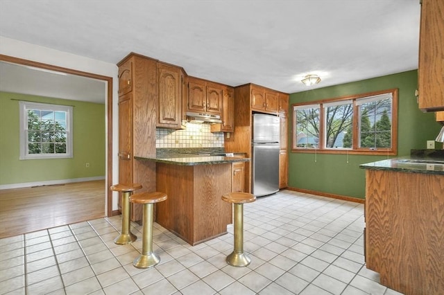 3 Norman Ave, Newburyport, MA 01950 - kitchen with freestanding refrigerator, under cabinet range hood, decorative backsplash, a peninsula, and baseboards